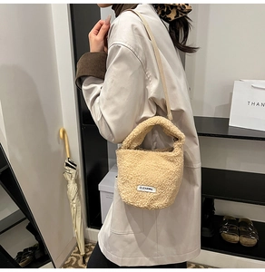 Detail of beige faux shearling bucket bag with CLEAR K logo and woven shoulder strap