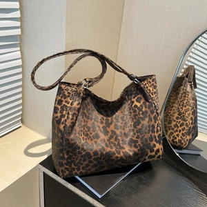 Large leopard print tote bag with leather texture in a vintage indoor aesthetic setting