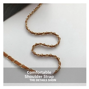 Détail de la chaîne dorée tressée avec un bracelet en cuir marron pour sac