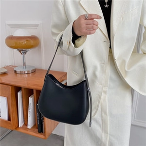 Minimalist black matte hobo bag worn on shoulder in a stylish lifestyle interior setting