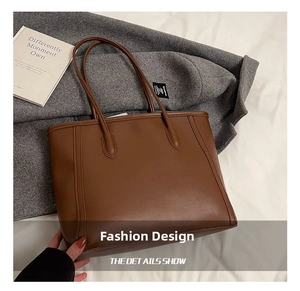 Close-up of the dark brown leather tote bag showing fine stitching and matte texture