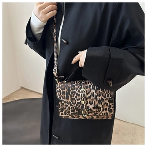 Lifestyle view showing the stylish leopard print crossbody bag worn with a black wool coat