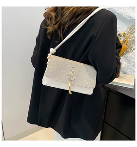 Close-up of cream white crossbody bag featuring rhinestone flap and golden tassel detail