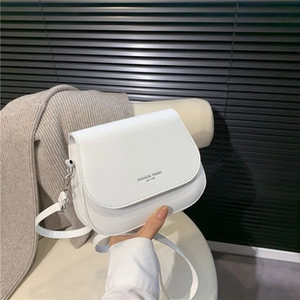 Detail of white saddle bag with FASHION TREND text and minimalist leather texture