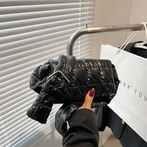Close-up of black quilted puffer tote bag featuring shiny fabric and silver buckle detail
