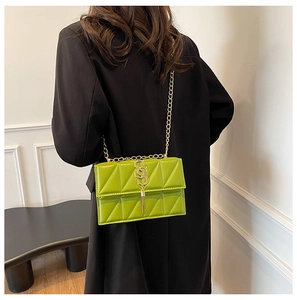 Detail view of lime green quilted chain shoulder bag with gold hardware worn by a model