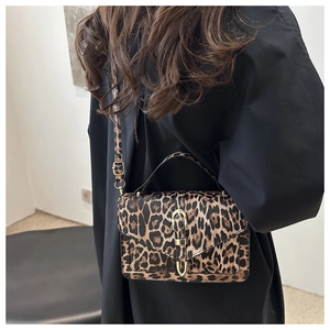 Detail of leopard print crossbody bag featuring a U-shaped gold metal lock and handle