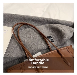 Detail of the slender dark brown leather handle on a minimalist commute tote bag