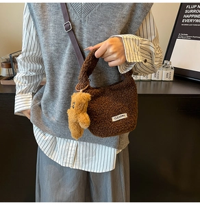 Detail of dark brown faux shearling bucket bag with cute bear charm and woven logo tag