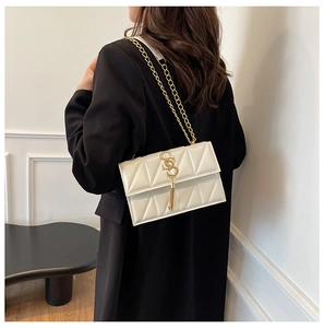 Close-up of white crossbody bag featuring triangle quilting and gold chain strap