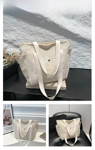 Detail view of large white canvas tote bag with front snap pocket and side storage pockets
