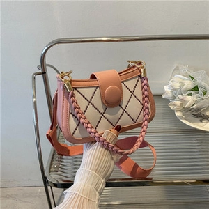 Detailed view of pink and white quilted tote bag with woven handle on metal shelf