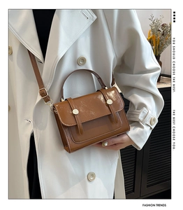 Detailansicht einer braunen Vintage-Handtasche mit Glanzoptik und goldenem Magnetverschluss