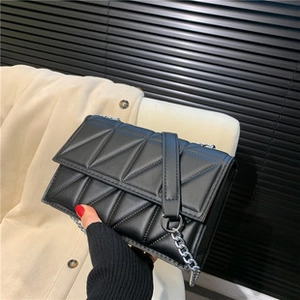 Close-up of black tote bag featuring triangular quilted texture and silver chain strap
