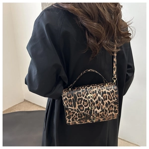 Detail of vintage leopard print crossbody bag featuring a golden metallic clasp and strap