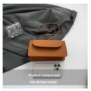 Vue détaillée du sac bandoulière en cuir caramel avec chaîne sur un blazer gris