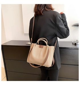 Close-up of khaki tote bag with contrast straps worn as a stylish shoulder bag