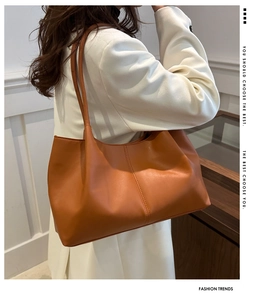 Close-up of brown leather tote bag showing large capacity and smooth texture on a model