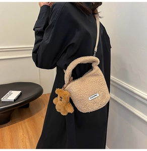 Detail of plush faux shearling bucket bag with brown teddy bear charm and logo patch