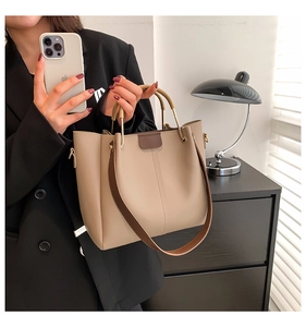 Detail of elegant beige faux leather tote bag with brown circular handles and gold hardware