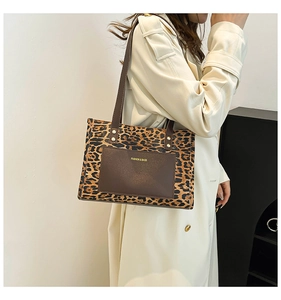Close-up of leopard print tote bag with brown leather pocket detail shown on model