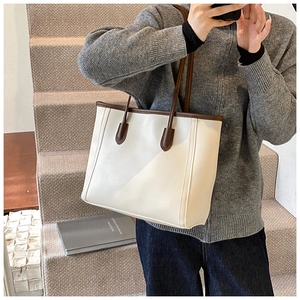 Retro cream leather tote bag with brown handles worn by model on stone steps