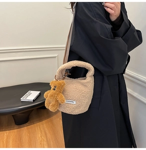 Detail of plush lamb wool bucket bag with cute bear charm and woven shoulder strap