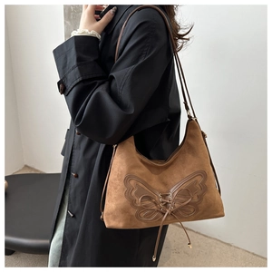 Détail du sac croissant en daim caramel avec motif papillon à lacets décoratifs