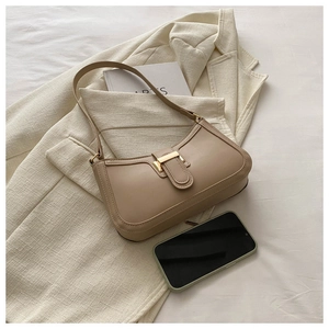 Detailed view of beige baguette bag featuring a gold rectangular buckle on a blazer