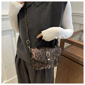 Close-up of leopard print crossbody bag with metallic clasp and adjustable strap