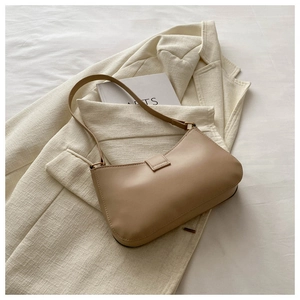 Detail of light brown retro faux leather underarm bag on white suit and art book