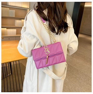 Detail of purple quilted leather crossbody bag with gold chain strap and fringe tassel