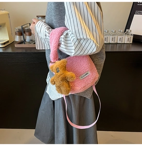 Detail of pink plush shoulder bag with CLEAR letter logo and a cute brown bear charm