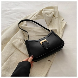 Close-up of black retro square shoulder bag with gold metal buckle on white blazer