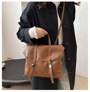 Lifestyle shot of a brown vintage tote bag with dual metal buckles and shoulder strap