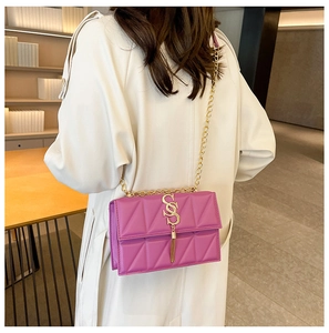 Detail of purple quilted shoulder bag with gold SS logo and fringe on a model