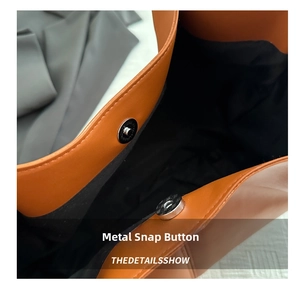 Detail of magnetic closure on orange leather tote bag with precise stitching