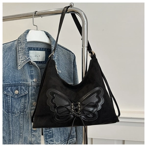 Détail du cabas en daim noir avec écusson papillon et finitions de laçage croisées