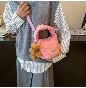 Detail of pink plush teddy bag featuring a woven label and cute brown bear pendant