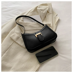 Detail of black matte leather hobo bag with gold metal buckle on a beige blazer background
