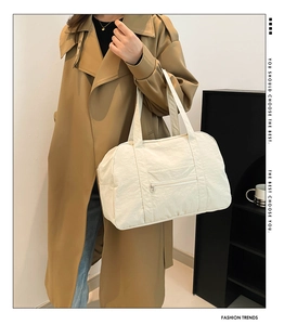 Detail of cream nylon travel tote bag showing soft texture and front zipper pocket
