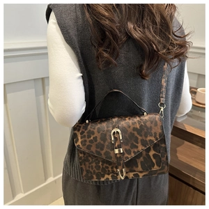 Detail of vintage leopard print crossbody bag with metallic buckle on a model