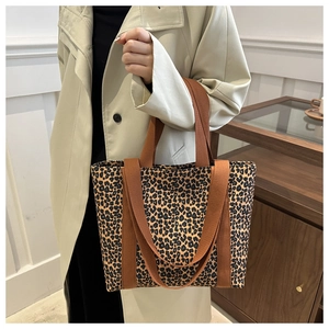 Grand sac fourre-tout à imprimé léopard avec anses tressées porté par un modèle