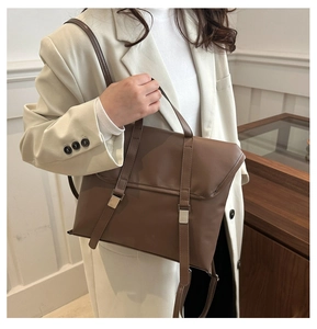 Detailed view of brown matte leather shoulder bag with decorative straps and silver buckles