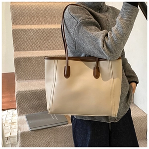 Detail of beige tote bag with brown leather trim and fine stitching on stairs