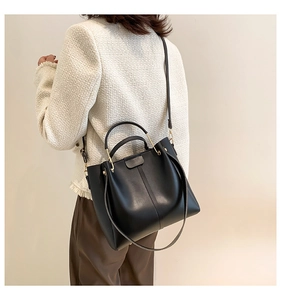 Elegant black PU leather tote bag with gold hardware shown on shoulder by model