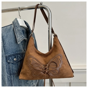 Détail du sac hobo en daim marron avec broderie papillon et design de sangle croisée