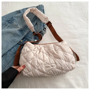 Close-up of quilted puffer bag with diamond stitching and adjustable brown textile strap