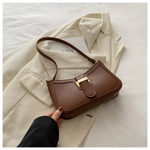 Detail of dark brown leather baguette bag with a striking gold rectangular clasp
