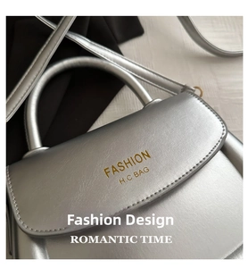 Detail shot of silver metallic leather saddle bag with top handle and gold foil branding